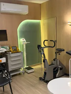 Sala de cardiologia, com bicicleta de teste de esforço e nicho em arco iluminado.