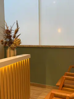 Canto da sala de espera, com arranjo de flores secas sobre o balcão.